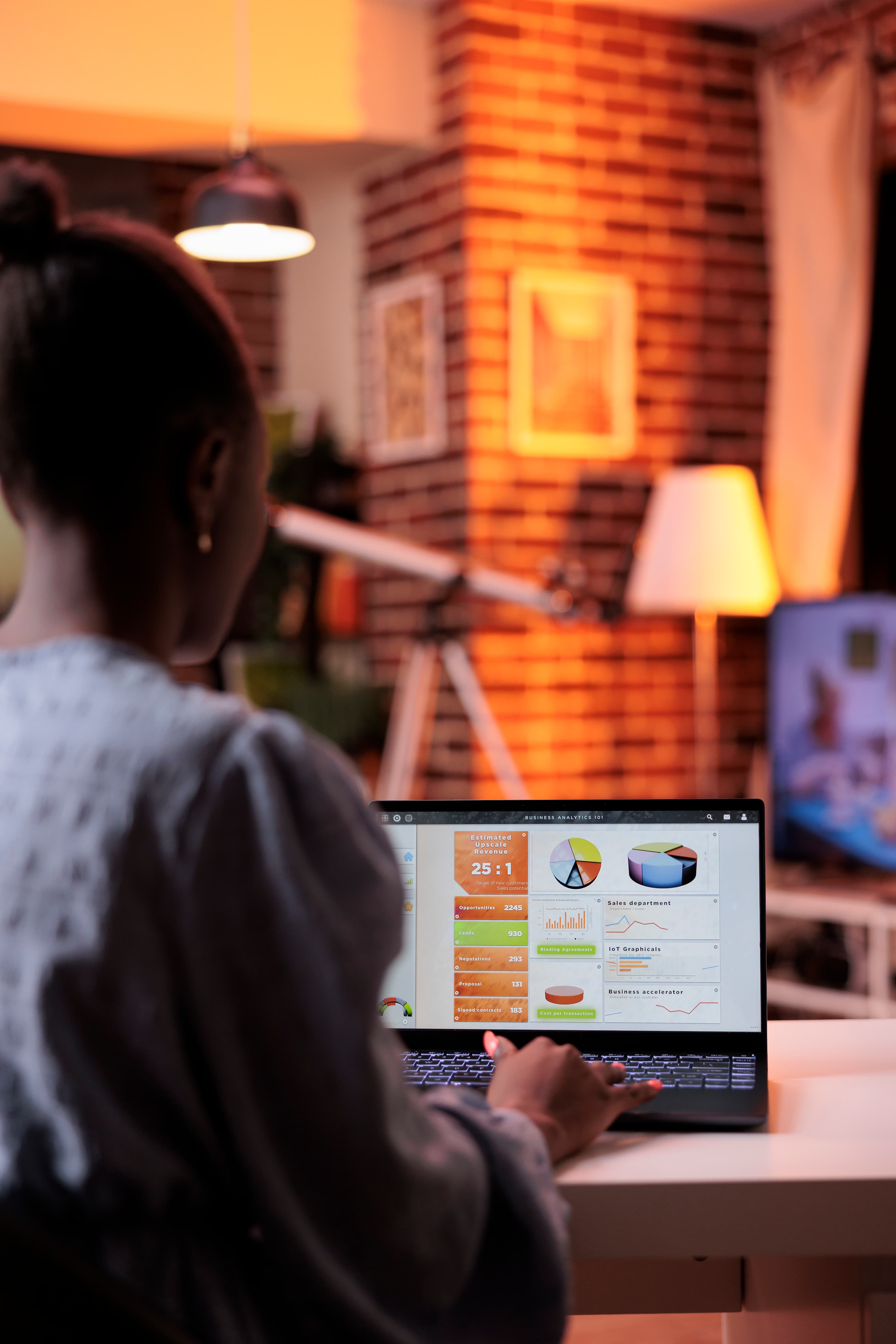 A business analyst reviewing charts and diagrams on a laptop in warm evening light.