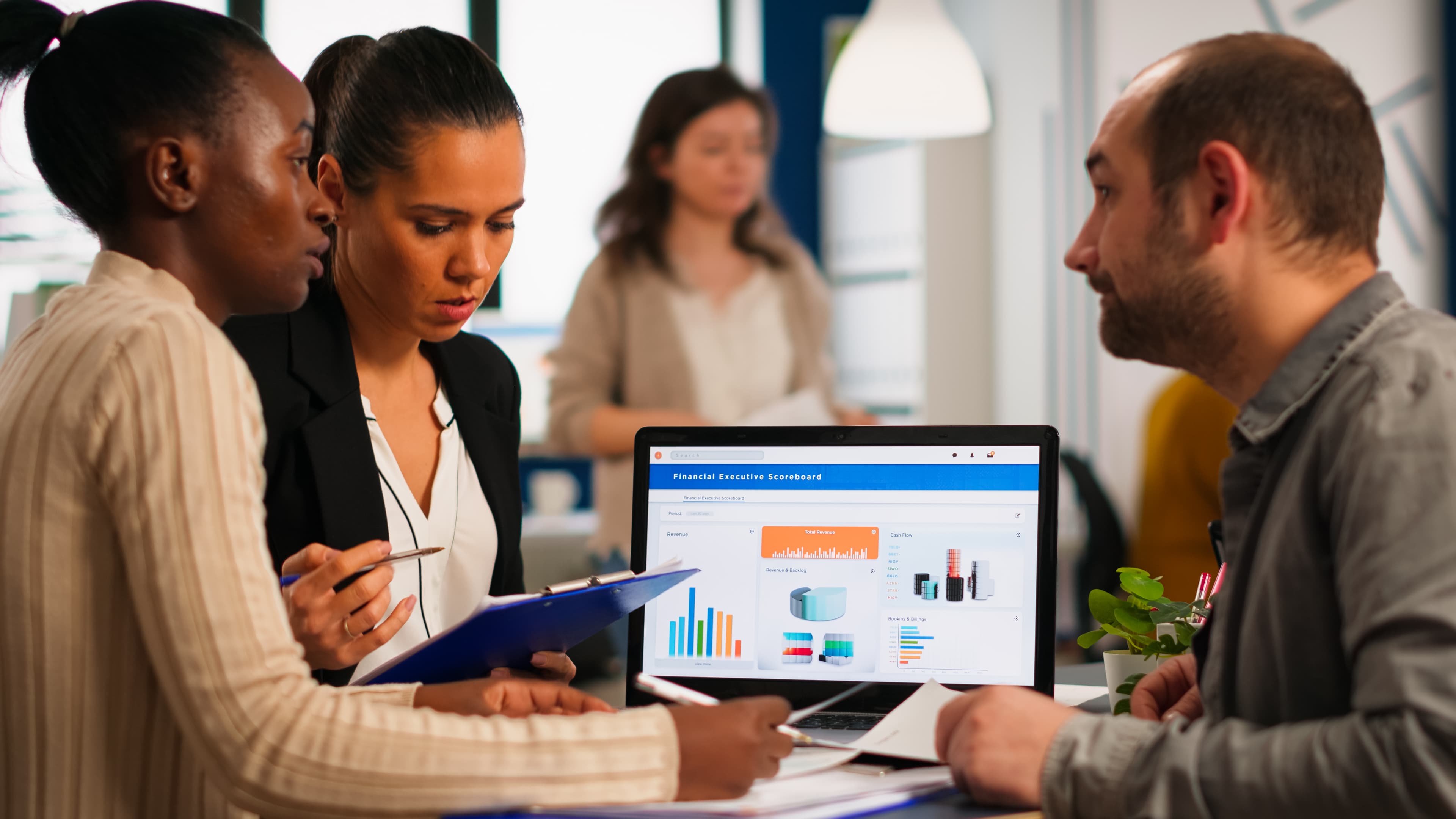 A diverse team reviewing financial and analytics data together around a laptop.