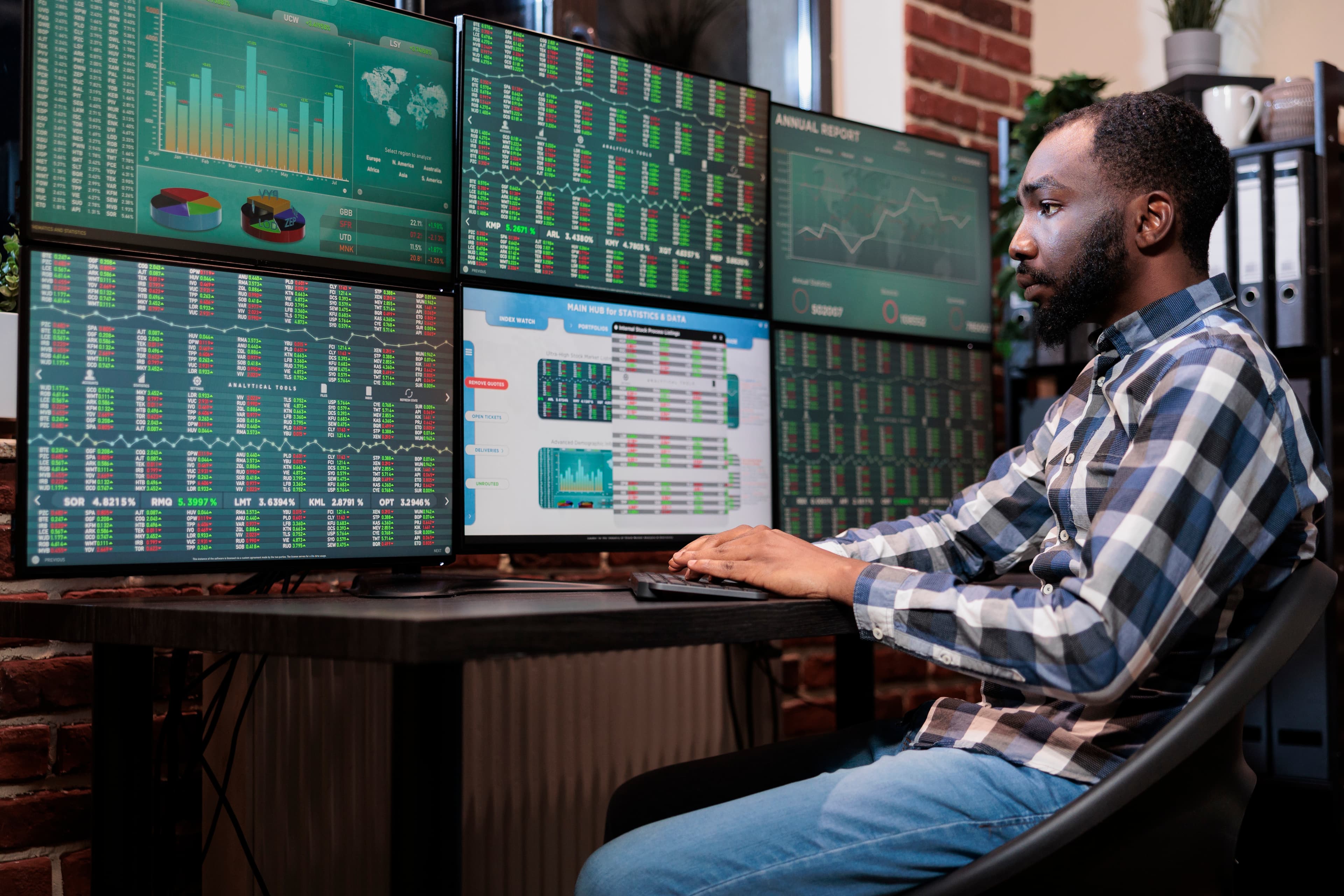 A data analyst monitoring live market and analytics dashboards across a multi-monitor workstation.